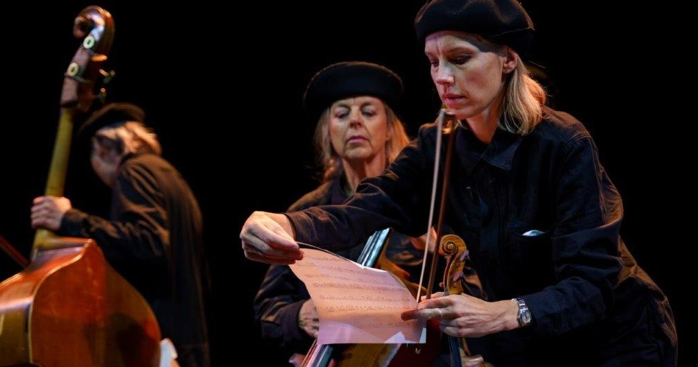 Tre svartklädda musiker med stråkinstrument och noter