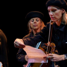 Tre svartklädda musiker med stråkinstrument och noter