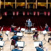 Foto som visar orkestern med en dirigent framför sig. 