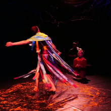 En bild som visar en snurrande dansare med tygremsor som flyger. Från föreställningen Skogens Ögon, Kai-En Butoh Company.