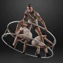 Tre cirkusartister som står inuti en hjulformad ställning