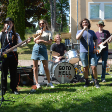 Ungdomar som spelar musik i ett band utomhus på sommaren.